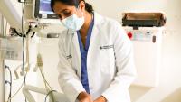 Dr. Megha Prasad standing over patient's bed, examining patient