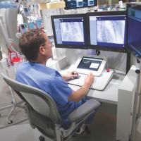 A man sitting in front of computer screens for medical purposes.